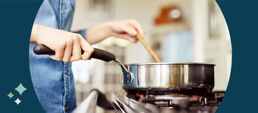 Home on a Hotplate - Person in denim shirt cooking in frying pan and holding a wooden spatula.