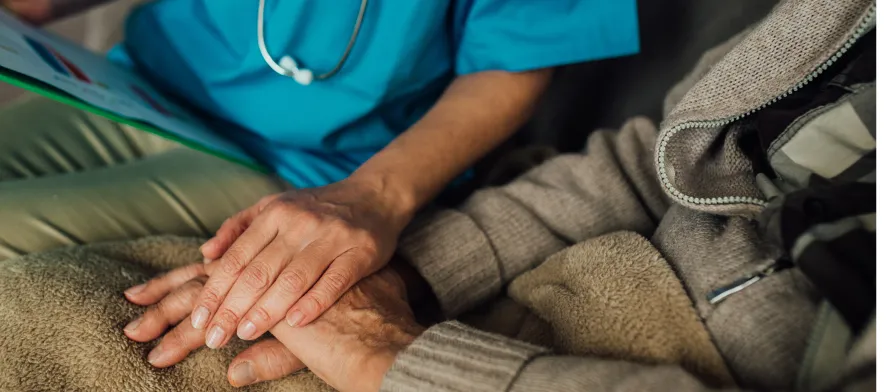 a long term care nurse holding hands with a patient